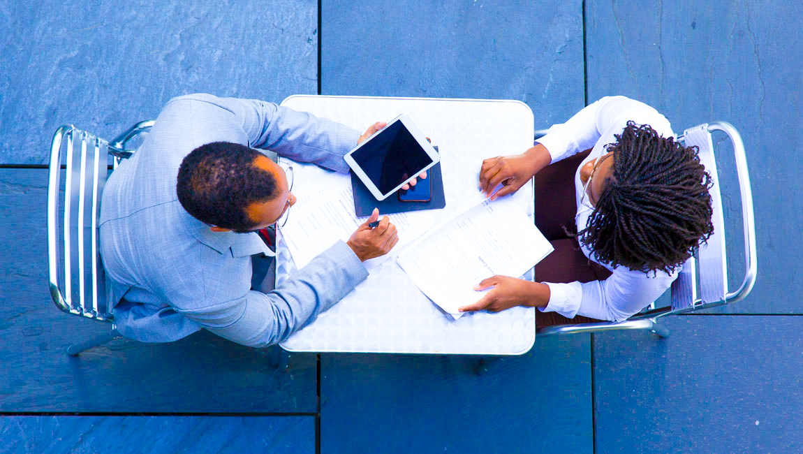 Aerial view of two colleagues at a table taking notes