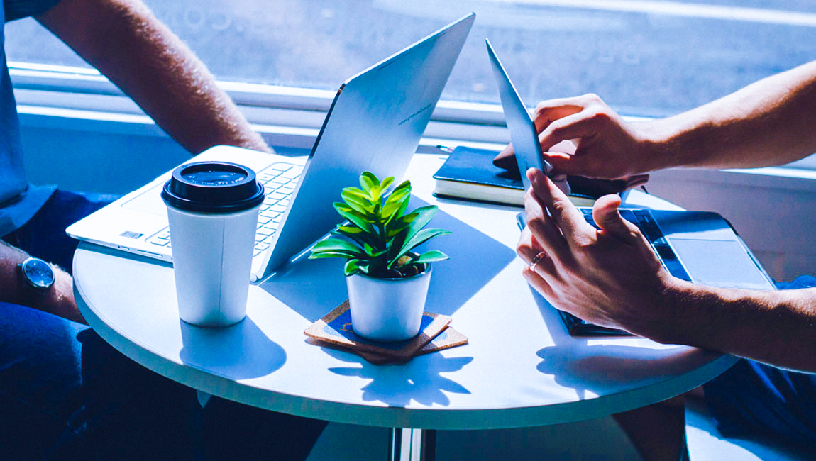 Two people seated at cafe table working on their laptops