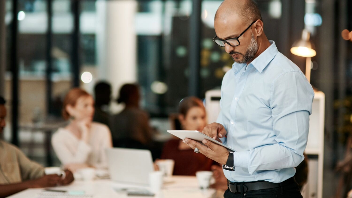 Businessman standing while looking at tablet before a meeting