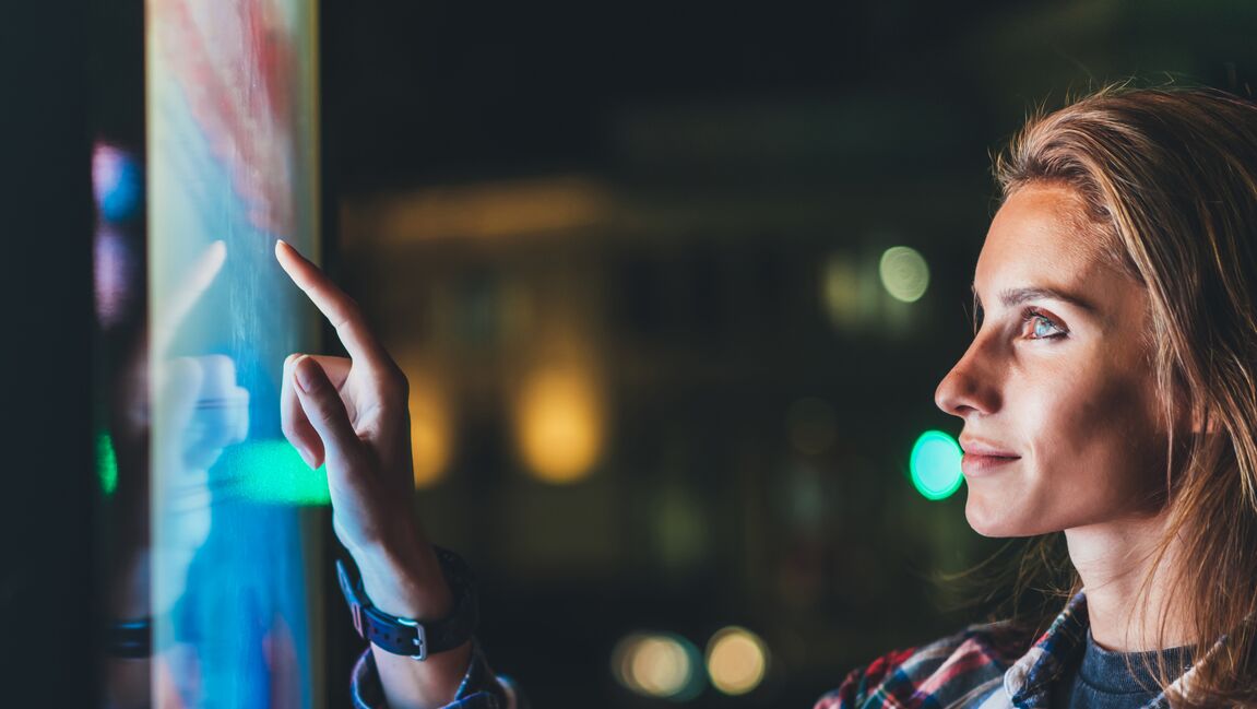 Woman in modern office pointing at interactive screen